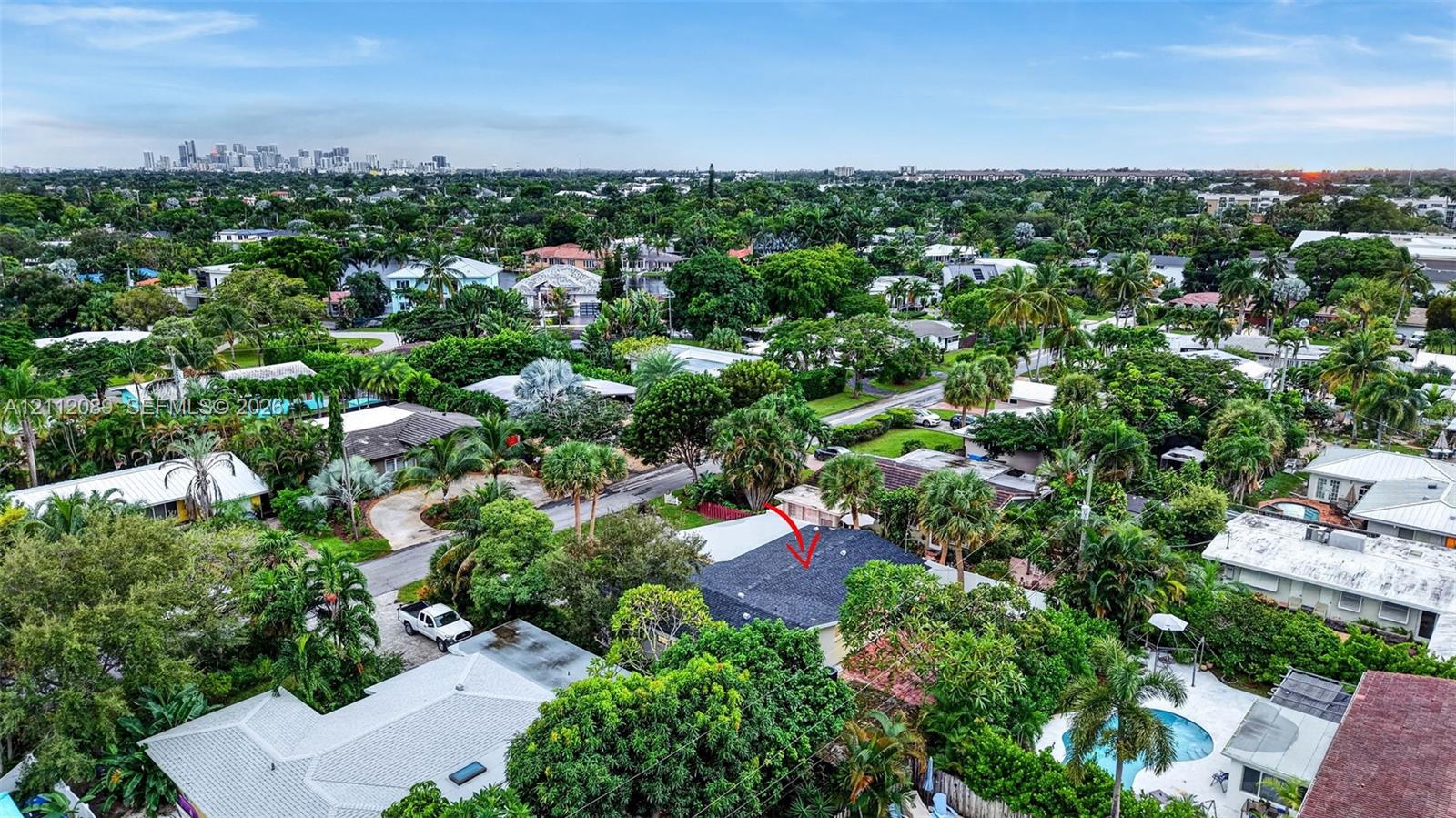 Aerial perspective featuring a dark shingle roof, established canopy trees, and an expansive residential landscape