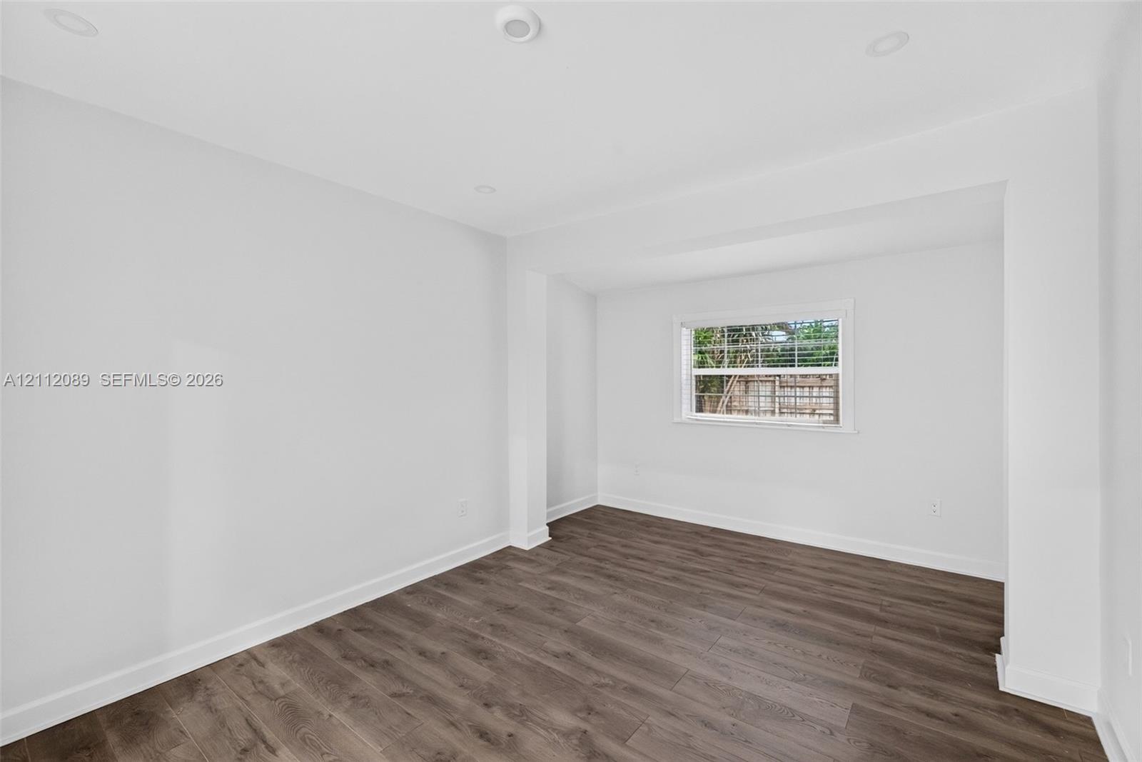 Neutral interior featuring wood-finish flooring, recessed lighting, and a single-pane window