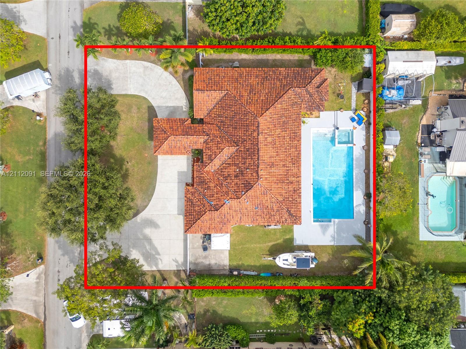 Aerial perspective featuring a tile roof, concrete driveway, in-ground swimming pool, and landscaped perimeter hedging