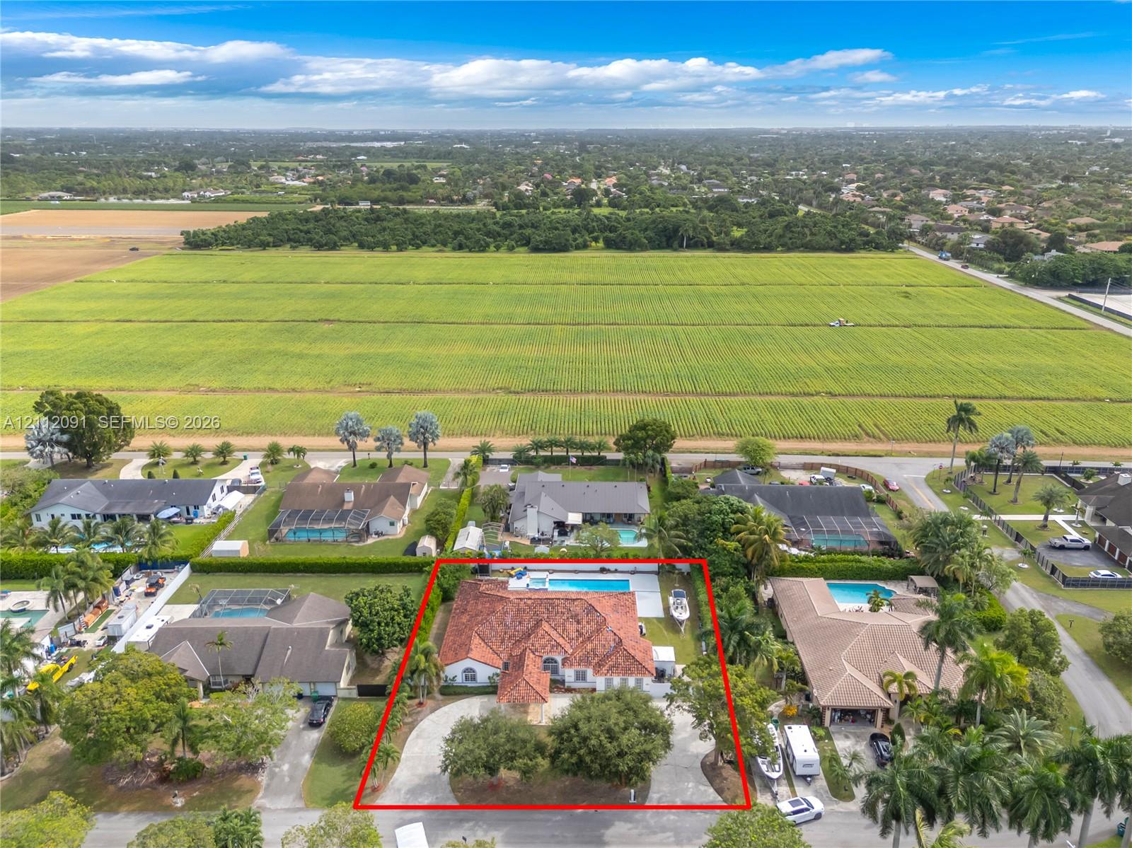 Single-story residence featuring a tile roof, circular driveway, swimming pool, and mature perimeter landscaping