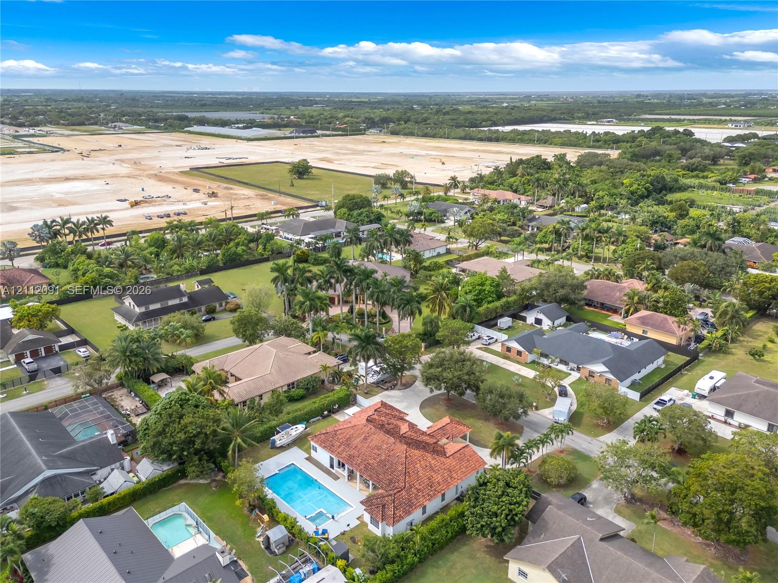 Aerial perspective featuring a terracotta-tiled roof, rectangular swimming pool, integrated spa, and concrete driveway on a landscaped lot