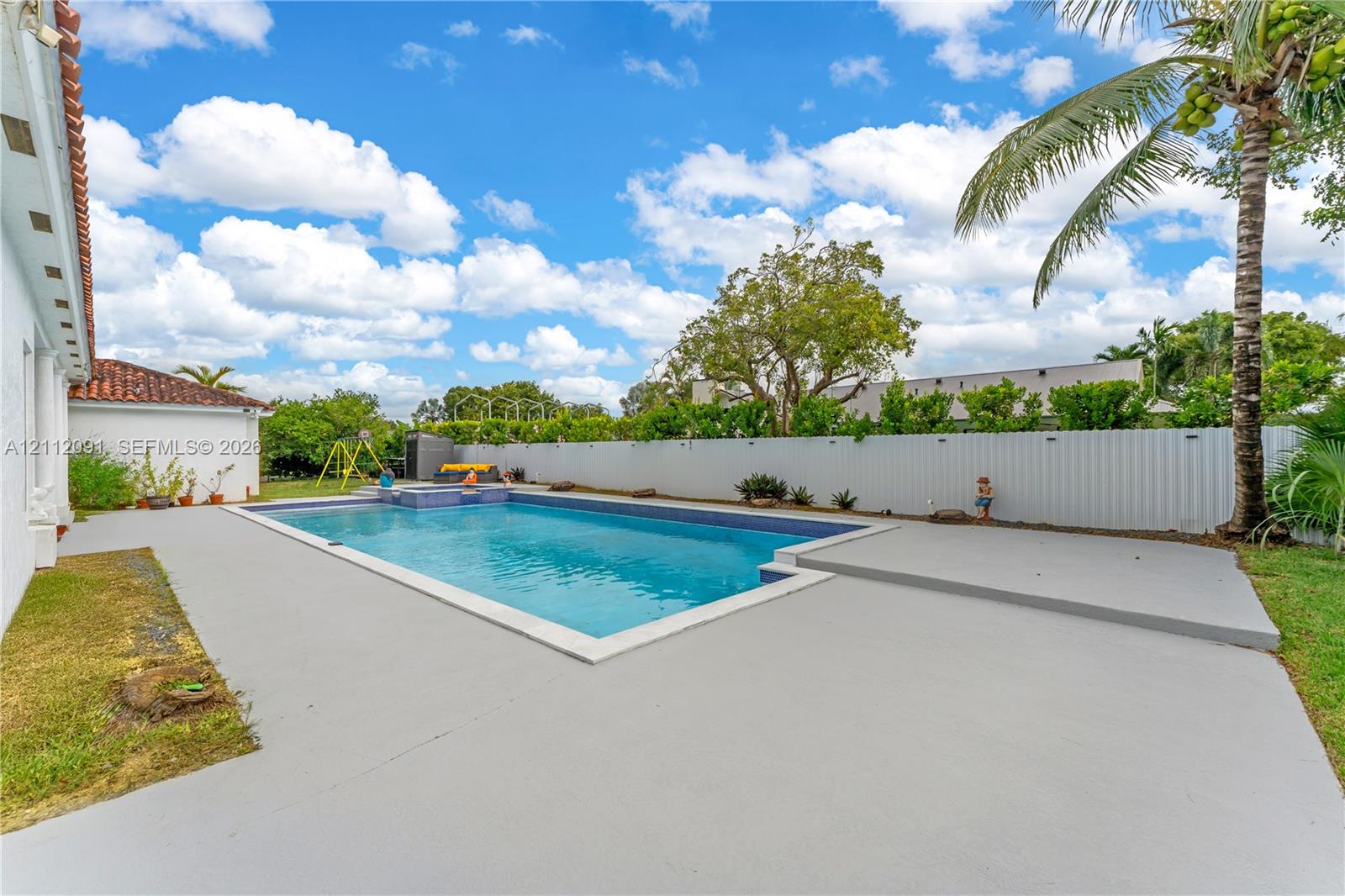 Outdoor swimming pool with integrated spa, concrete decking, and privacy fencing