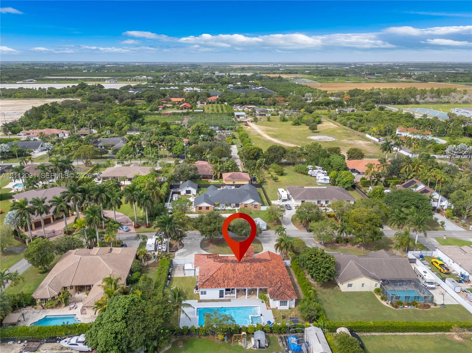 Aerial perspective of a residential property featuring a tile roof, an in-ground swimming pool with an attached spa, and a concrete driveway