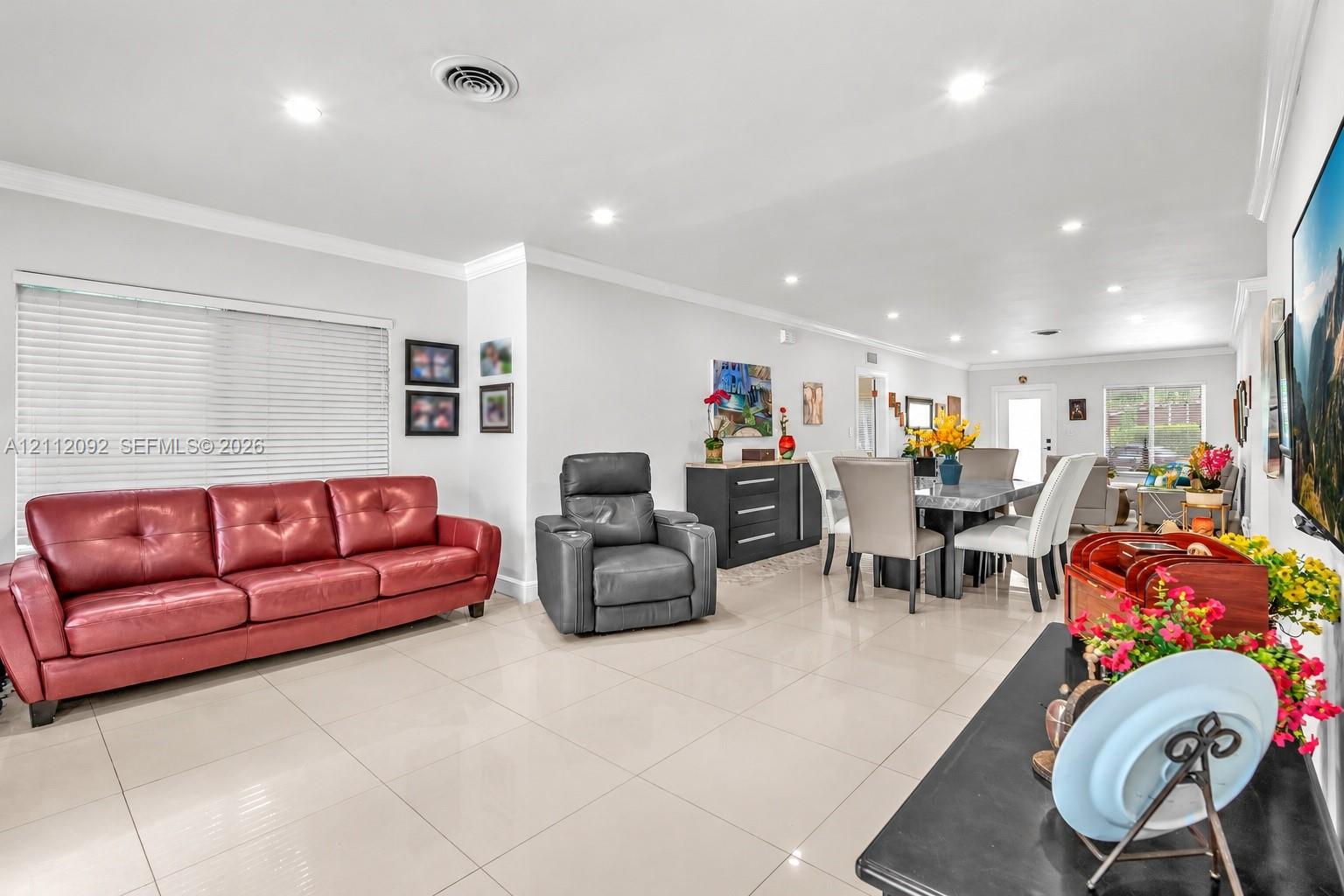 Open-concept interior featuring large-format tile flooring, recessed ceiling lighting, crown molding, and expansive windows with installed blinds
