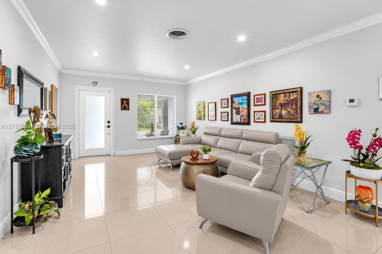 Neutral-toned polished tile flooring, recessed lighting, crown molding, and a front entry door featuring frosted glass paneling