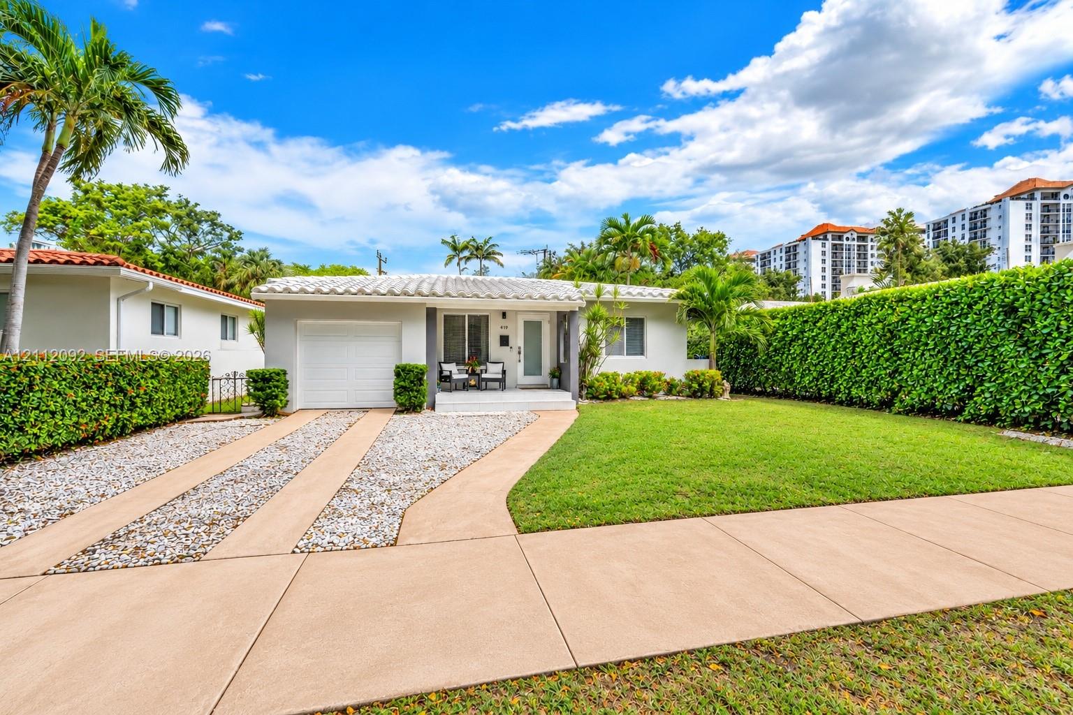 Single-story residence featuring a barrel tile roof, concrete driveway, attached garage, and manicured lawn