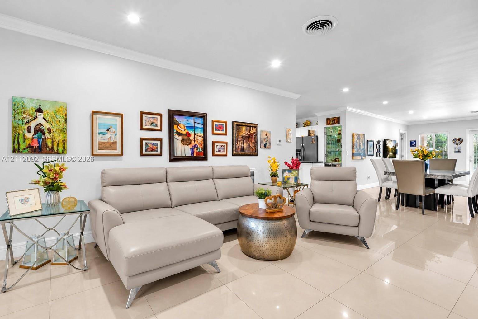 Open-concept interior featuring large-format tile flooring, recessed lighting, and crown molding
