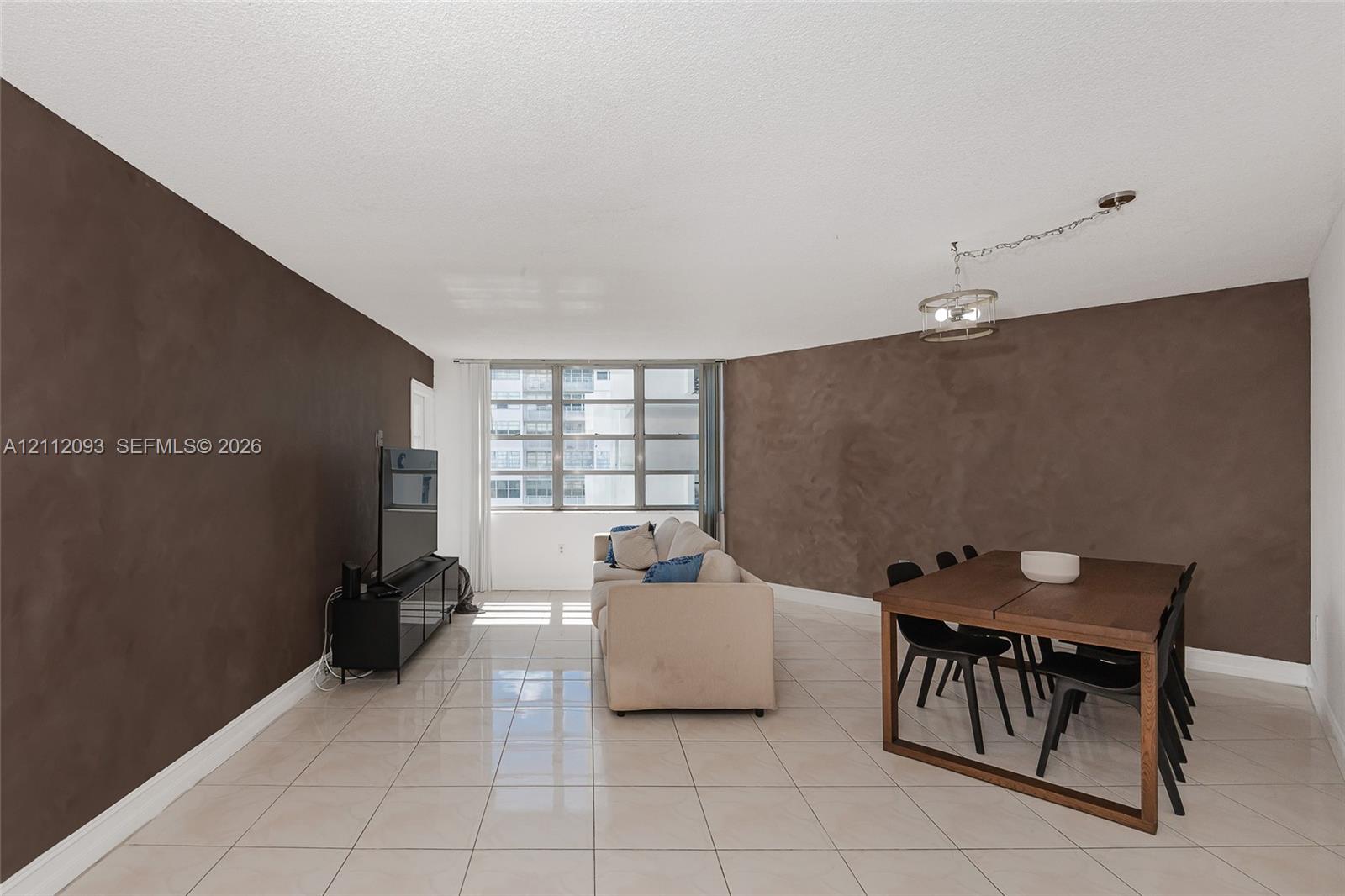 Open floor plan featuring large-format ceramic tile flooring, textured accent walls, and floor-to-ceiling multi-pane windows