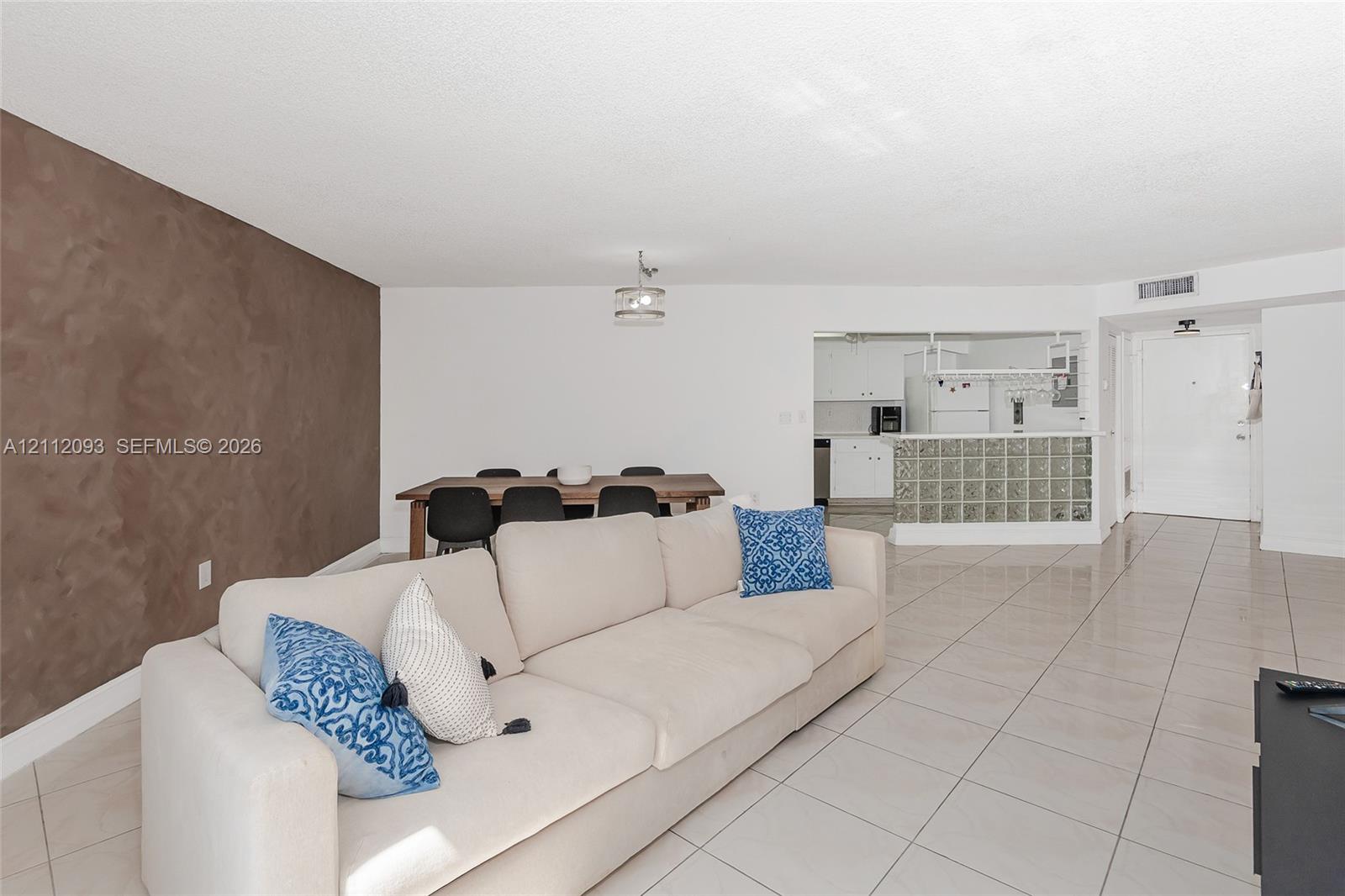 Neutral-toned tile flooring, accent wall with textured finish, glass block kitchen partition, and overhead semi-flush mount lighting Neutral-toned tile flooring, accent wall with textured finish, glass block kitchen partition, and overhead semi-flush mount lighting