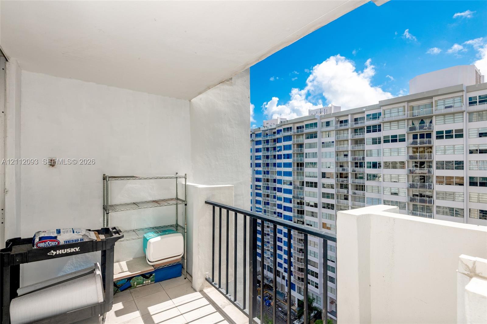 Covered balcony featuring tile flooring and a black metal railing