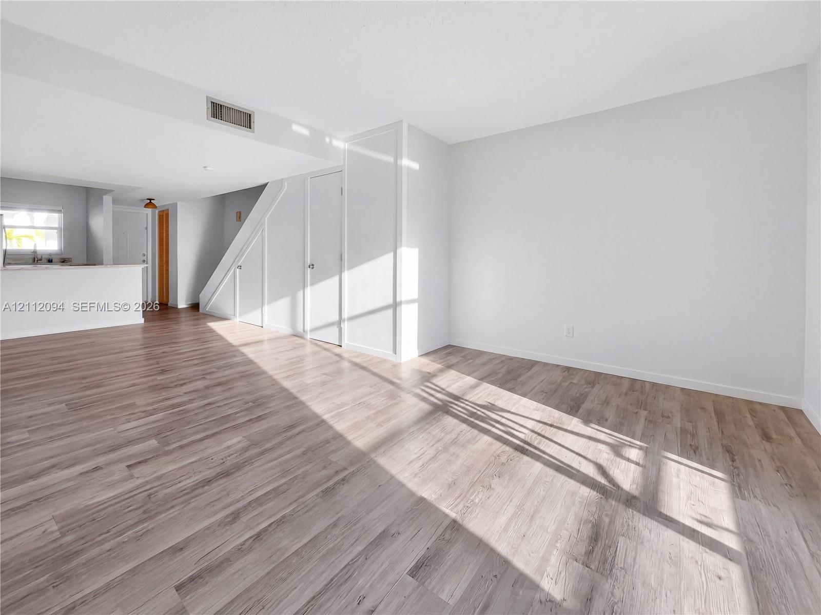Interior featuring neutral wall paint, wood-finish flooring, and built-in closet storage Interior featuring neutral wall paint, wood-finish flooring, and built-in closet storage