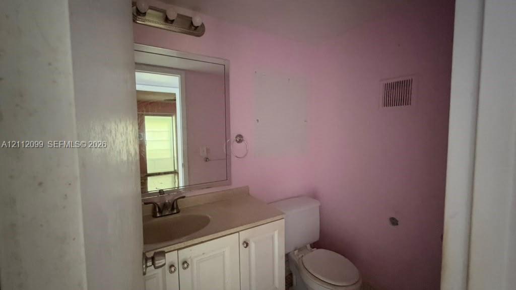 Bathroom featuring a white vanity cabinet with an integrated basin, a polished chrome faucet, a rectangular wall-mounted mirror, and a three-light vanity fixture
