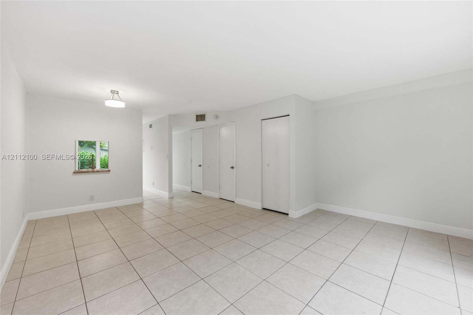 Neutral-toned interior featuring ceramic tile flooring, recessed ceiling lighting, and multiple interior closet doors