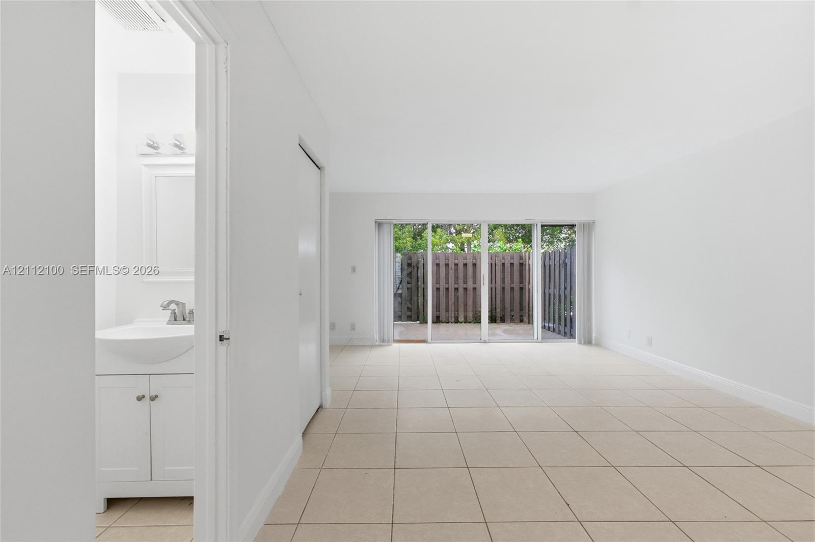 Interior featuring neutral ceramic tile flooring, sliding glass doors, and a bathroom vanity with a basin sink and integrated cabinet storage