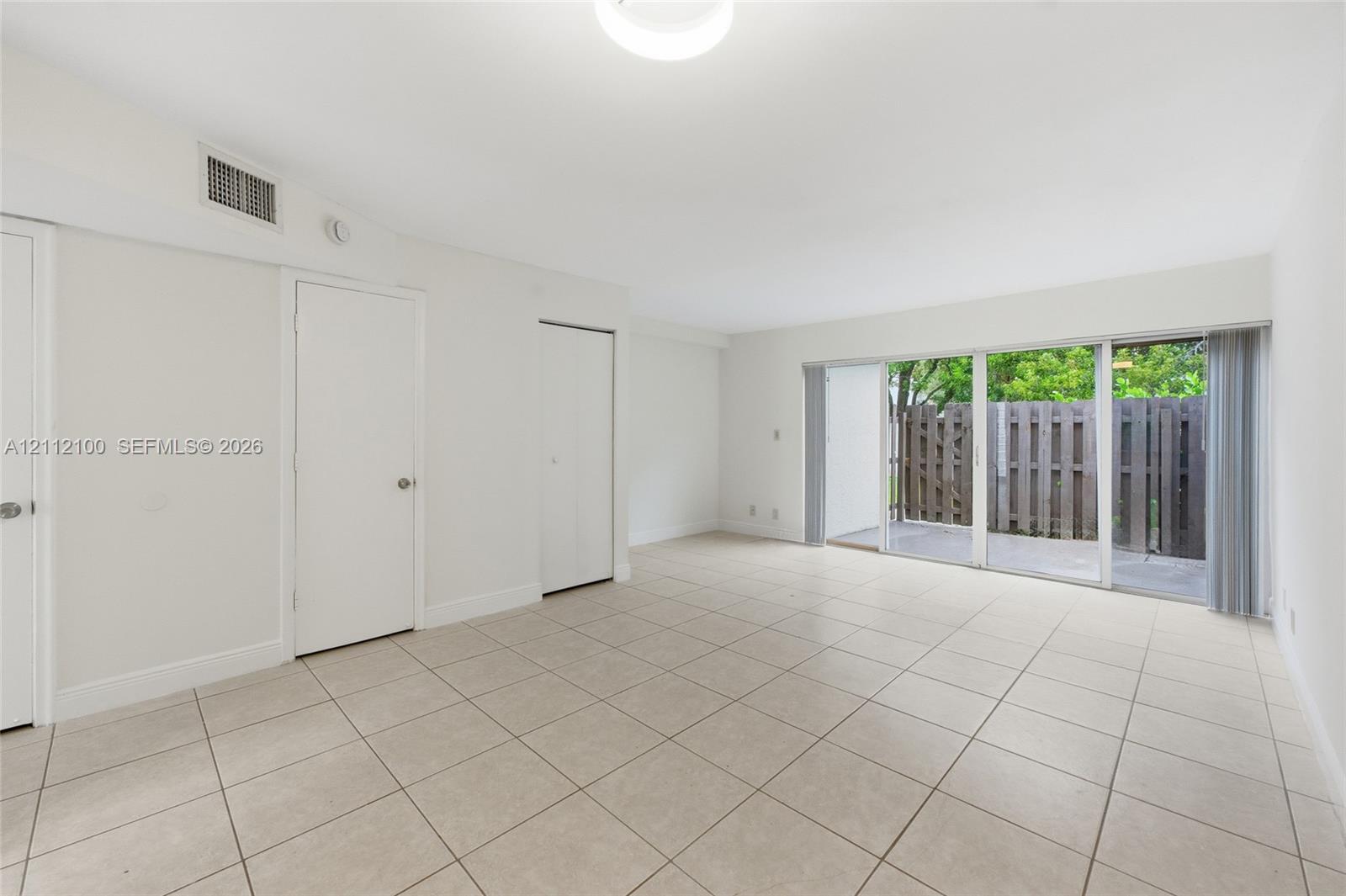 Neutral-toned ceramic tile flooring, sliding glass doors, and solid-core interior doors