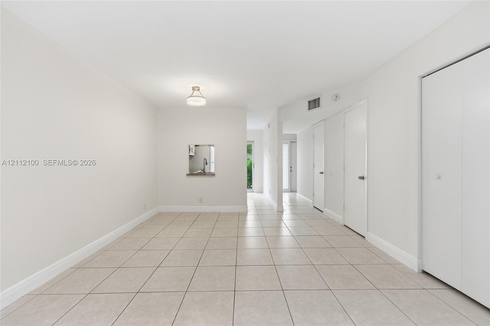 Neutral-toned tile flooring, recessed pass-through window, and minimalist flush-mount lighting