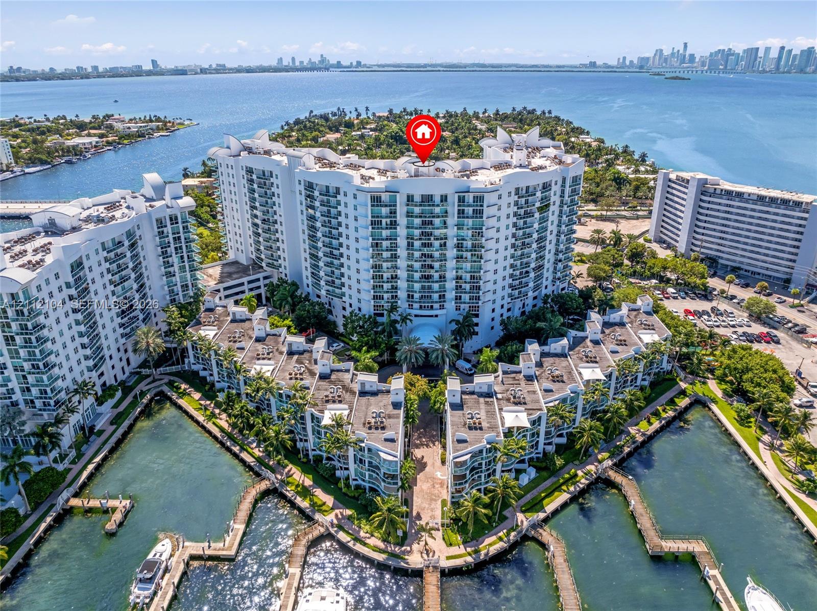 Aerial perspective of a waterfront residential complex featuring multiple deep-water boat slips, manicured tropical landscaping, and structural balconies overlooking the bay