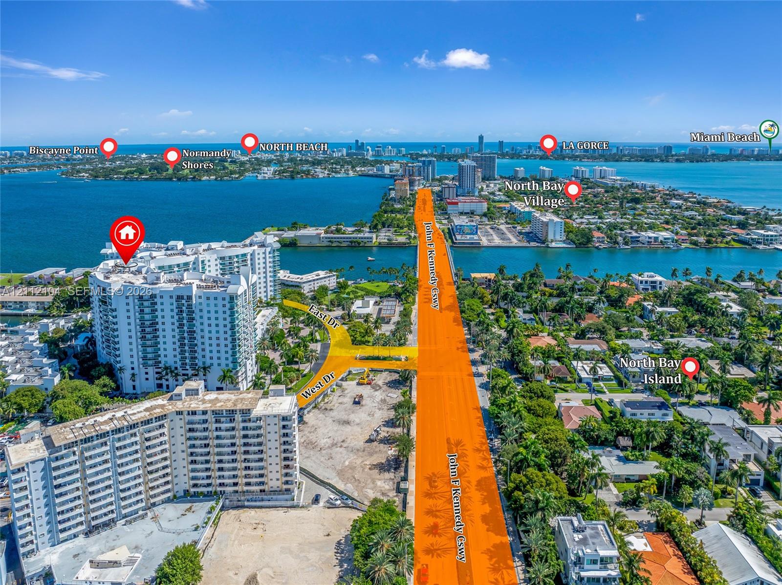Aerial perspective of a high-rise residential building situated on a waterfront peninsula with proximity to major thoroughfares