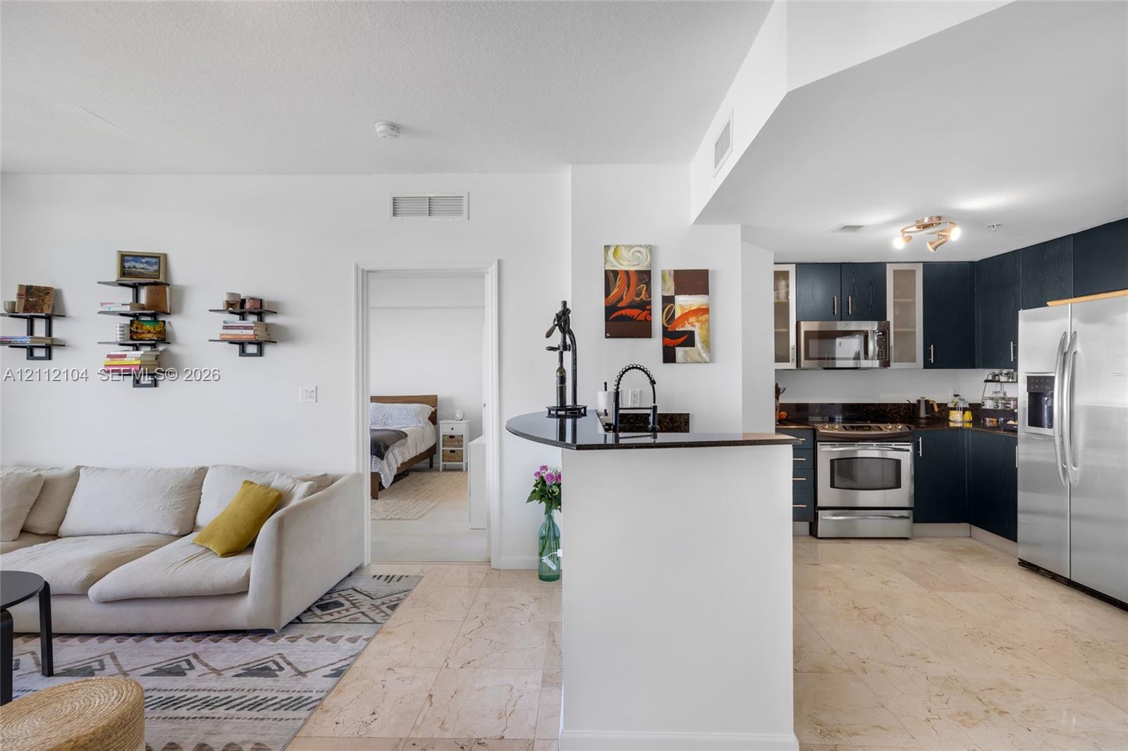 Kitchen featuring dark-finish cabinetry, stainless steel appliances, and a solid-surface breakfast bar with stone flooring throughout