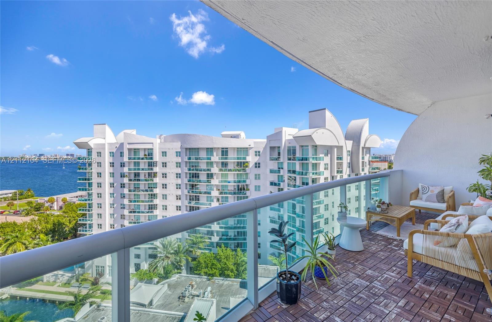 Covered balcony featuring modular wood-tile flooring and glass panel railing