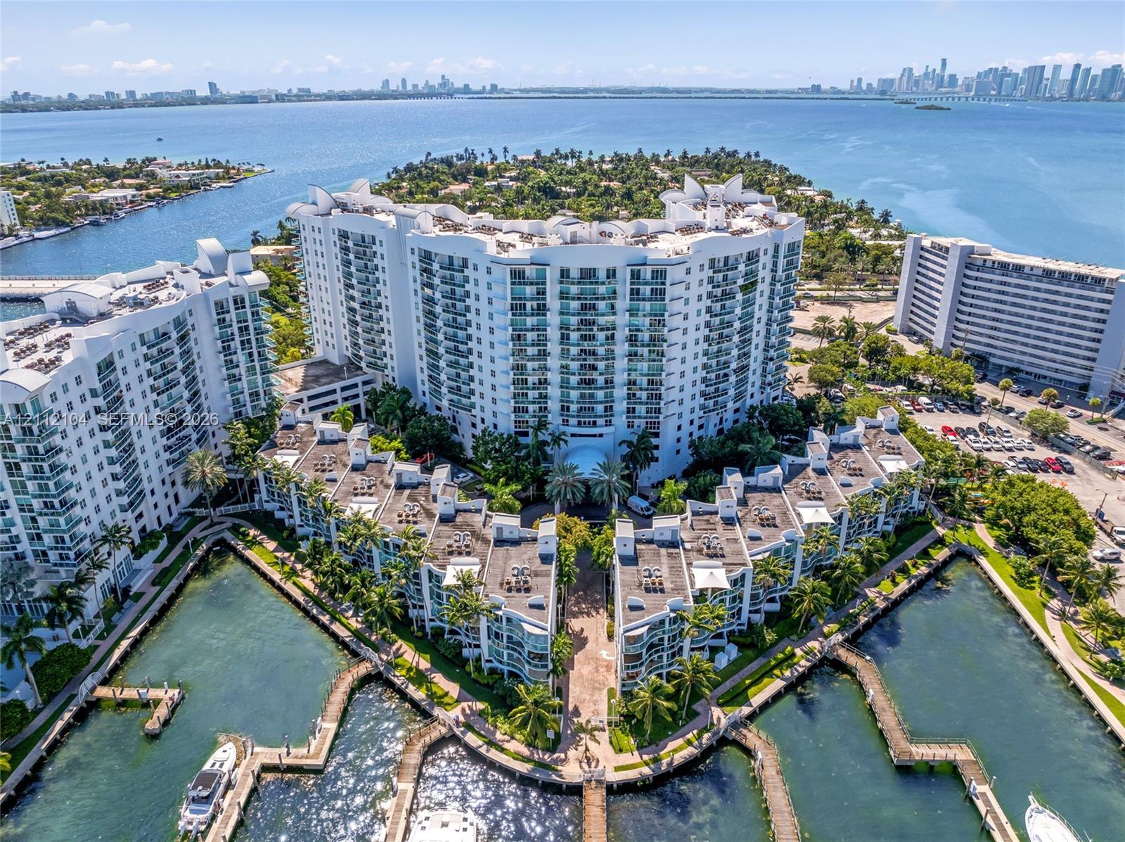 Waterfront high-rise complex featuring private boat slips, multi-level balconies, exterior stucco finish, and landscaped grounds