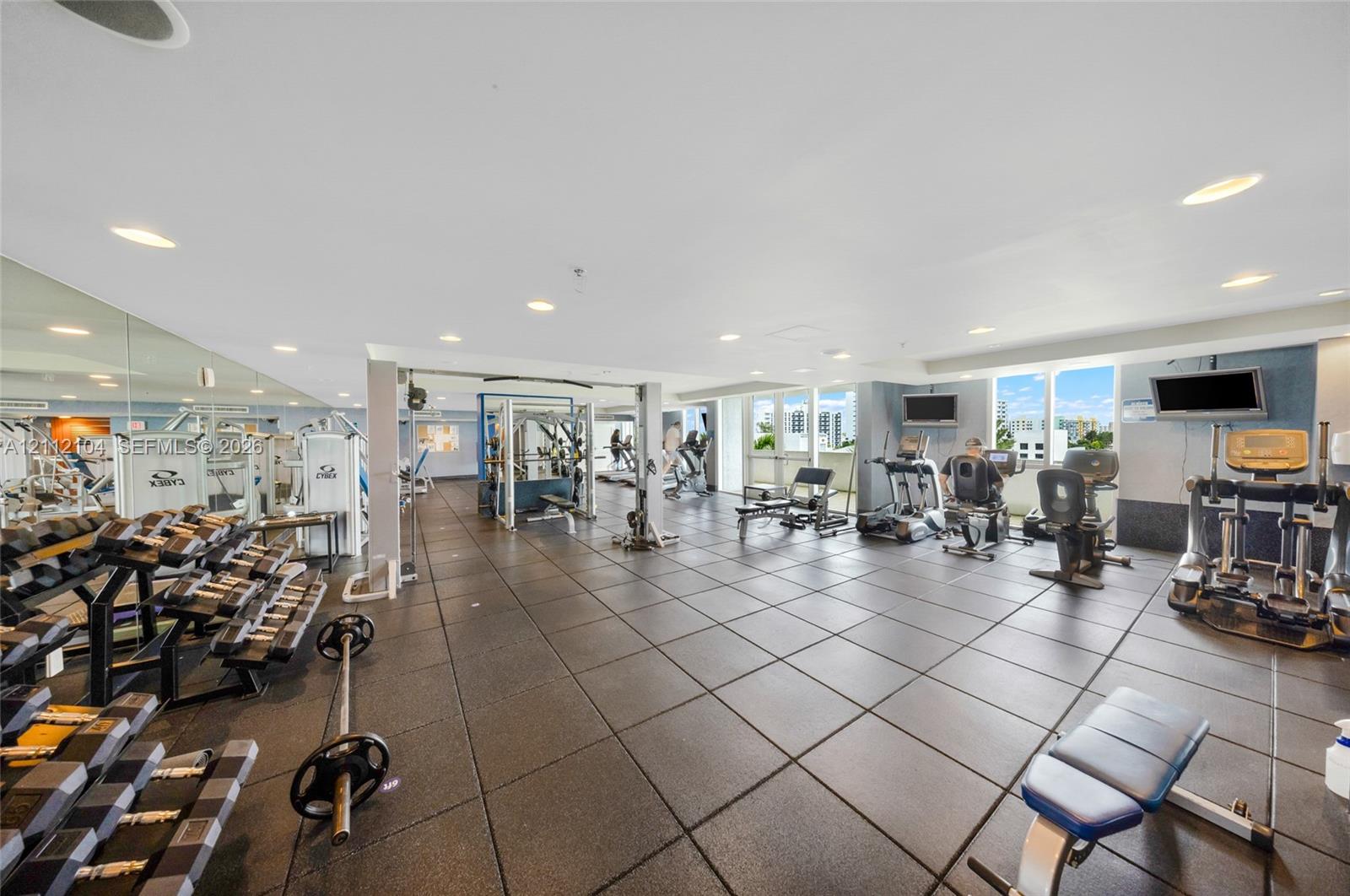 Fitness center featuring rubberized tile flooring, mirrored walls, recessed lighting, and expansive floor-to-ceiling windows