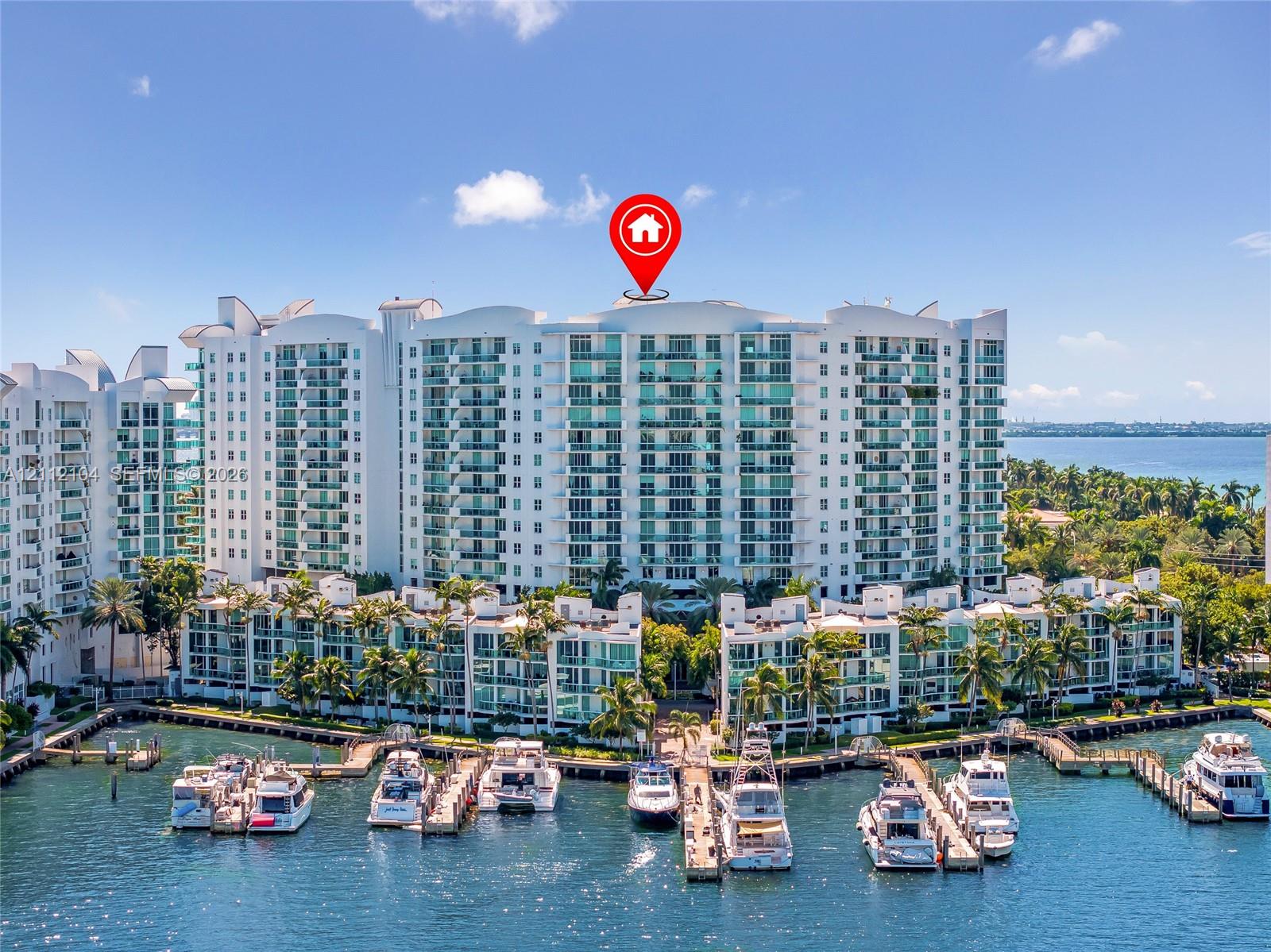 Multi-story waterfront residential complex featuring private boat slips, balconies with glass railings, and mature palm trees