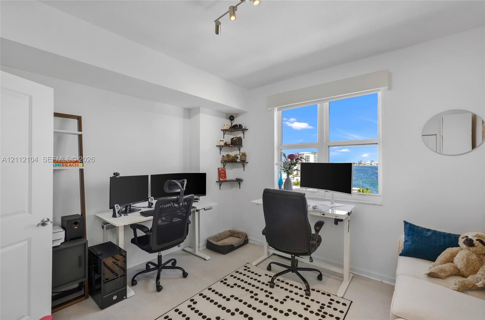 Room featuring a window with water backdrop, neutral wall tones, and overhead track lighting