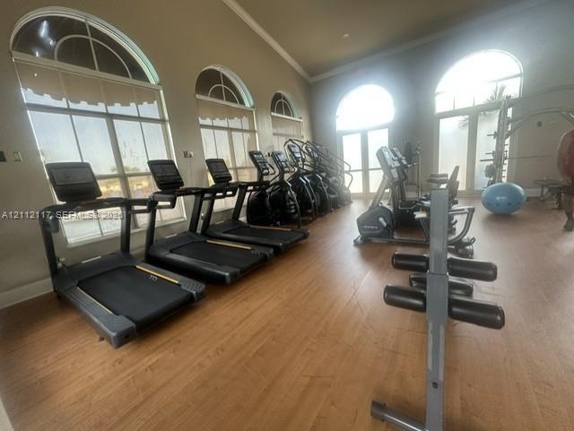 Fitness room featuring wood-finish flooring, vaulted ceilings, and arched windows