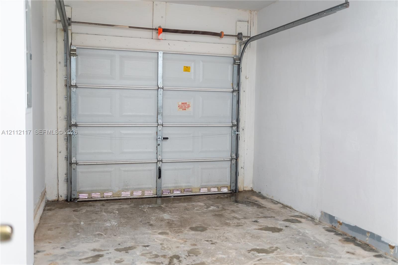 Enclosed garage space featuring a paneled sectional door, overhead tracks, and concrete flooring