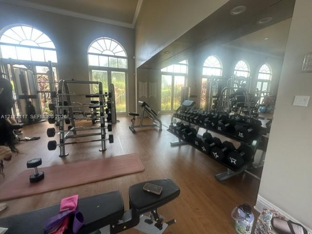 Spacious room featuring floor-to-ceiling wall mirrors, wood-finish flooring, recessed lighting, and arched windows with exterior access