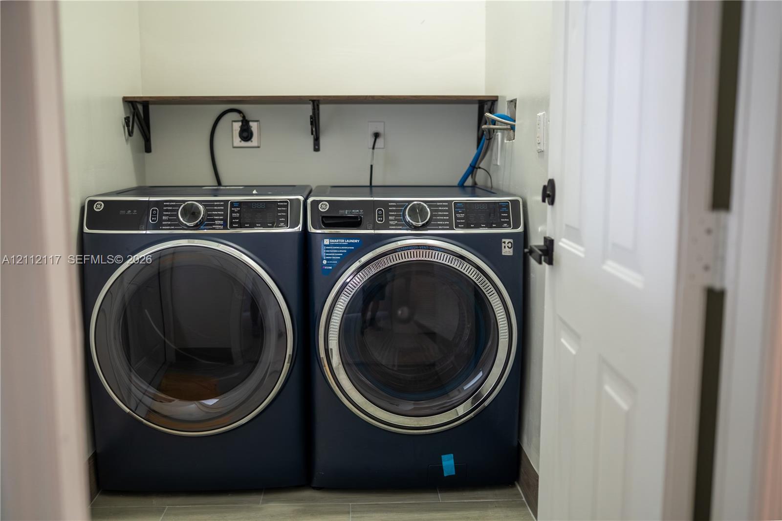 Laundry area featuring a wall-mounted shelf and tile flooring