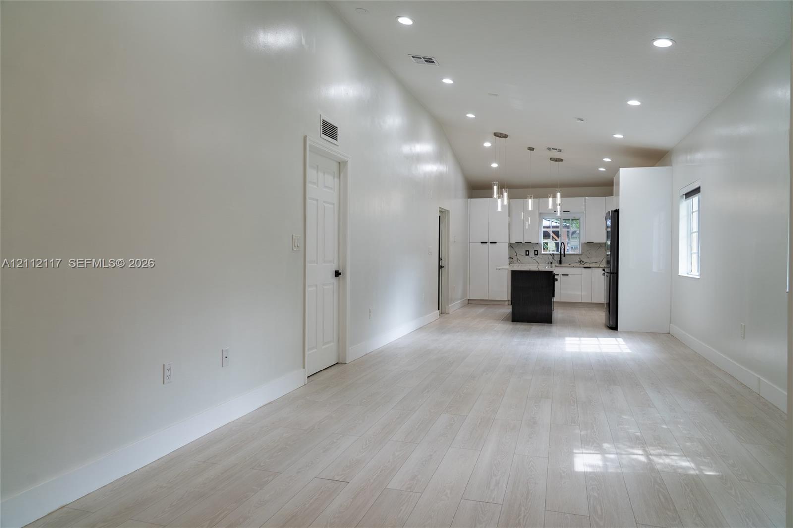 Vaulted ceilings, wood-finish flooring, recessed lighting, white cabinetry, and kitchen island Vaulted ceilings, wood-finish flooring, recessed lighting, white cabinetry, and kitchen island