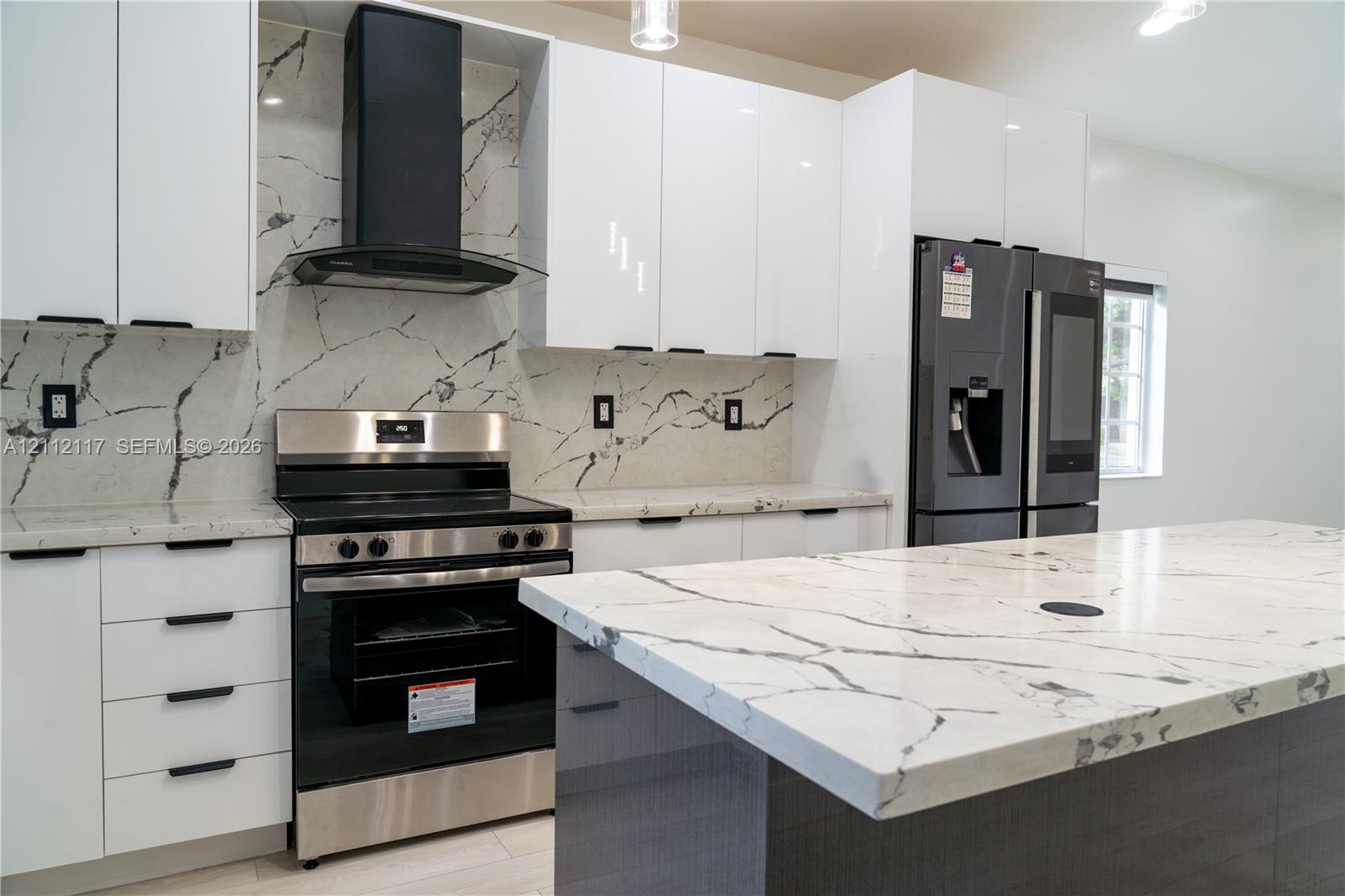 Kitchen featuring high-gloss white cabinetry, stone-patterned countertops, matching full-height backsplash, stainless steel range with a wall-mounted chimney hood, and a central island with integrated stone surfacing Kitchen featuring high-gloss white cabinetry, stone-patterned countertops, matching full-height backsplash, stainless steel range with a wall-mounted chimney hood, and a central island with integrated stone surfacing