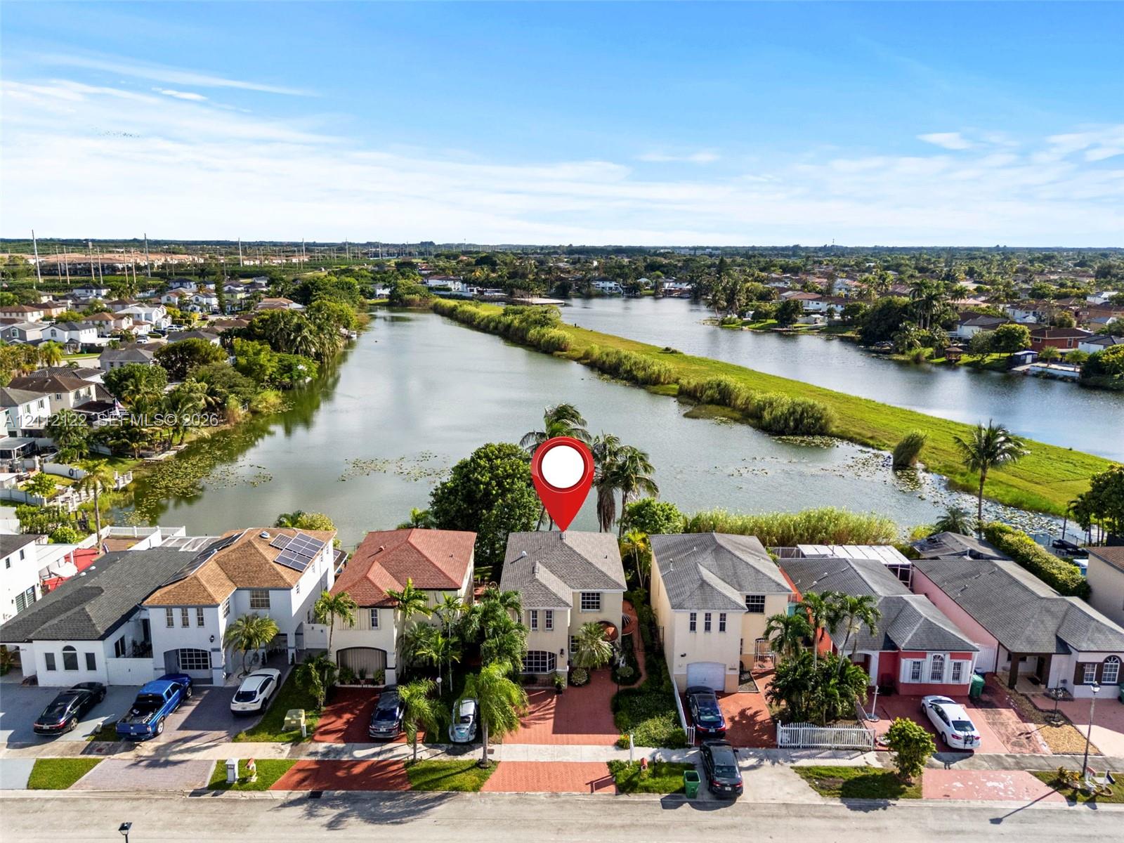 Two-story residence featuring a paved driveway, tile roofing, and placement on a waterfront lot