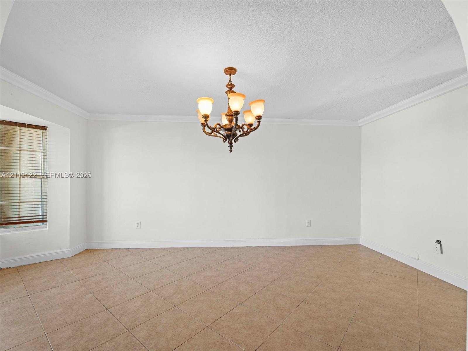 Interior space featuring tile flooring, crown molding, a multi-light metal chandelier, and a window with blinds