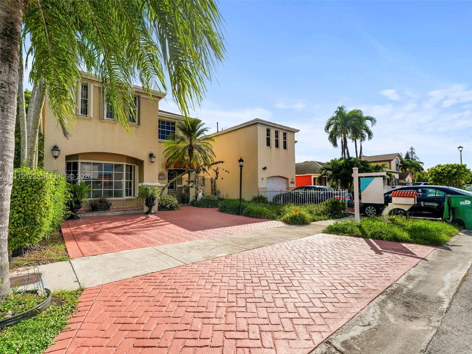 Stucco exterior featuring a multi-level facade, herringbone-patterned paved driveway, bay window, and attached garage