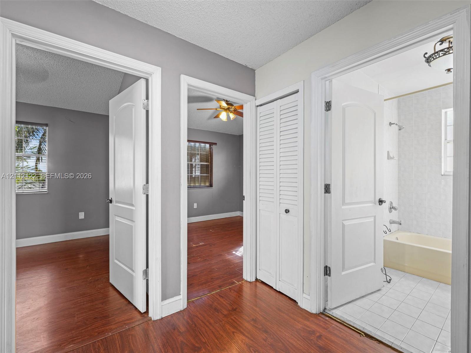 Hallway featuring wood-finish flooring, white paneled interior doors, and a louvered closet door