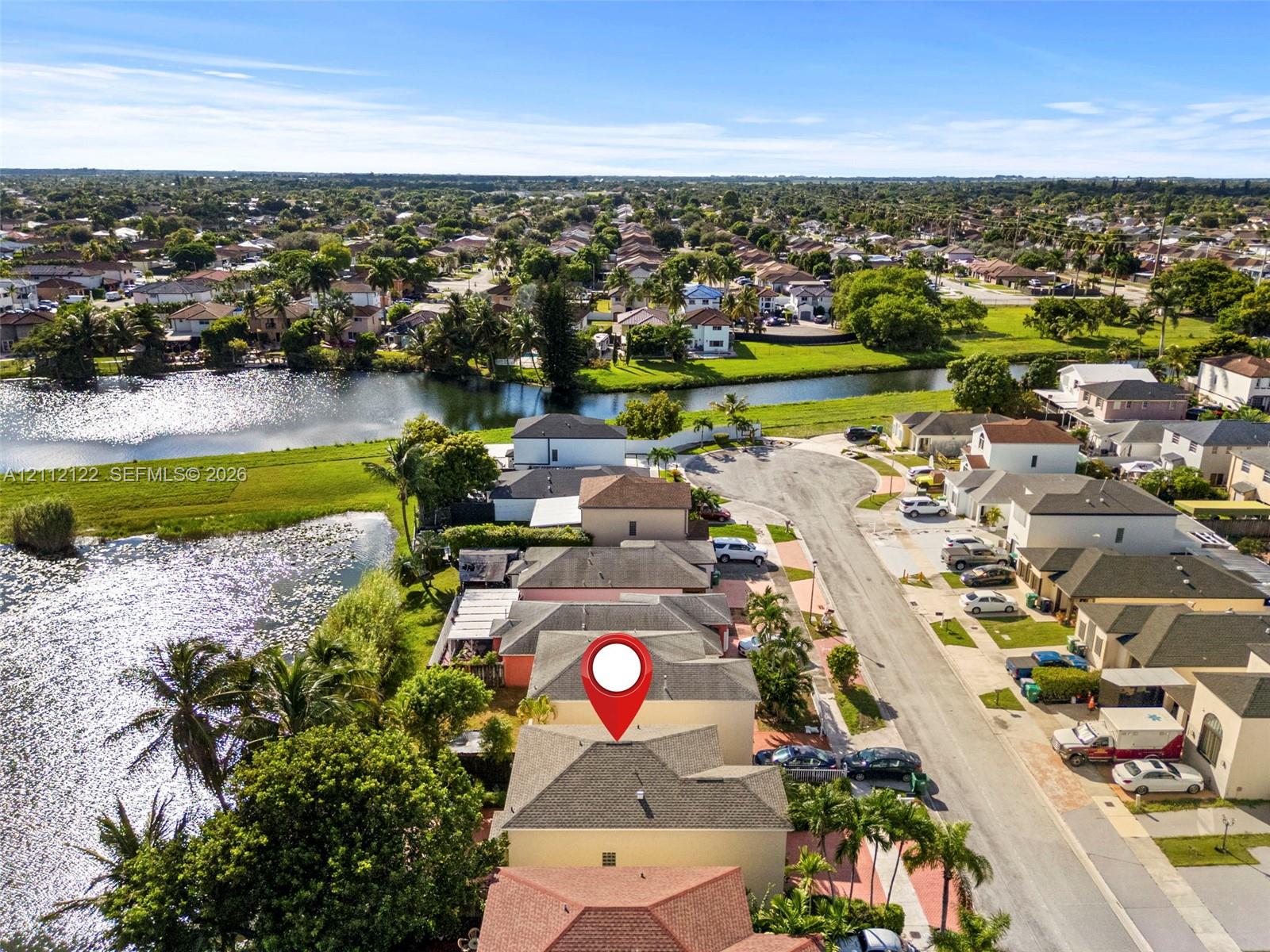 Aerial perspective showcasing a residential property with a multi-level roofline, situated on a waterfront lot featuring direct canal access and mature perimeter landscaping