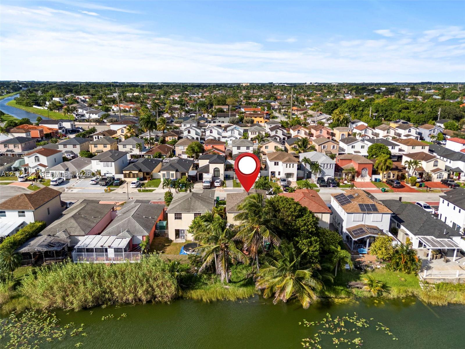Aerial perspective of waterfront property featuring a canal-side location, mature palm trees, and residential neighborhood setting