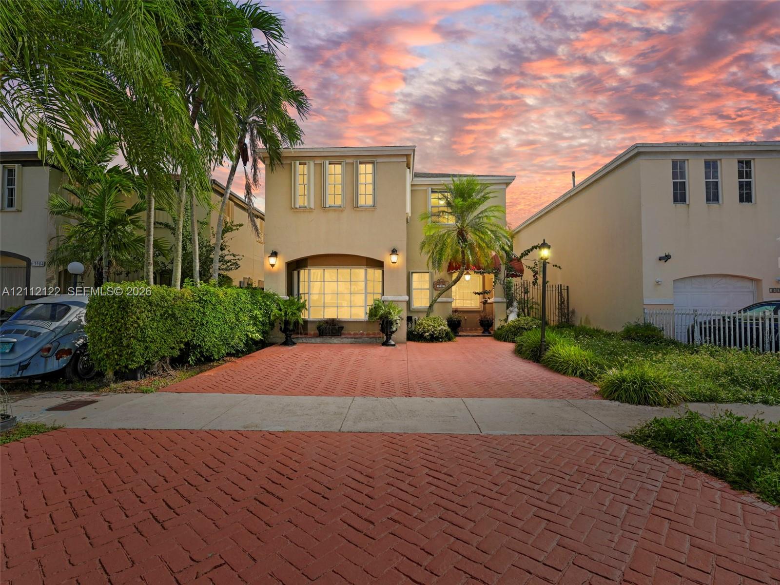Two-story exterior featuring a brick-paved driveway, recessed entryway with a bay window, and manicured landscaping