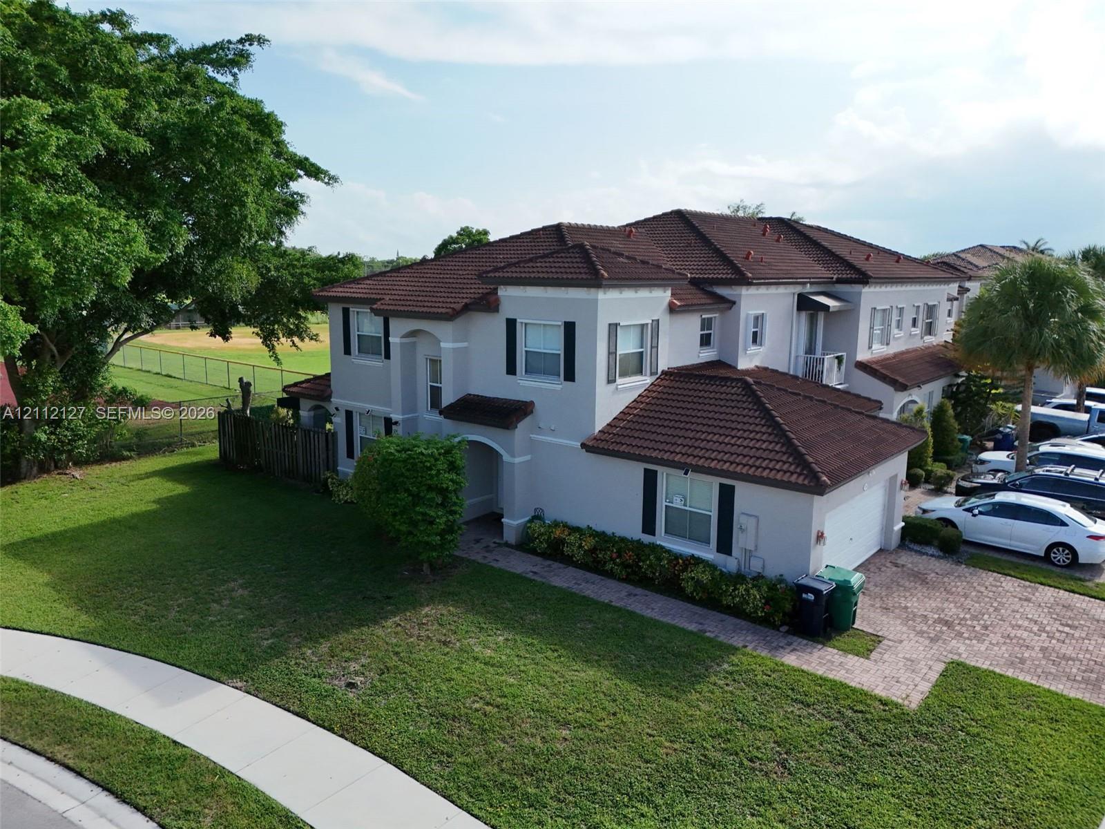 Multi-story residence featuring a tile roof, stucco exterior, paved driveway, and decorative exterior shutters