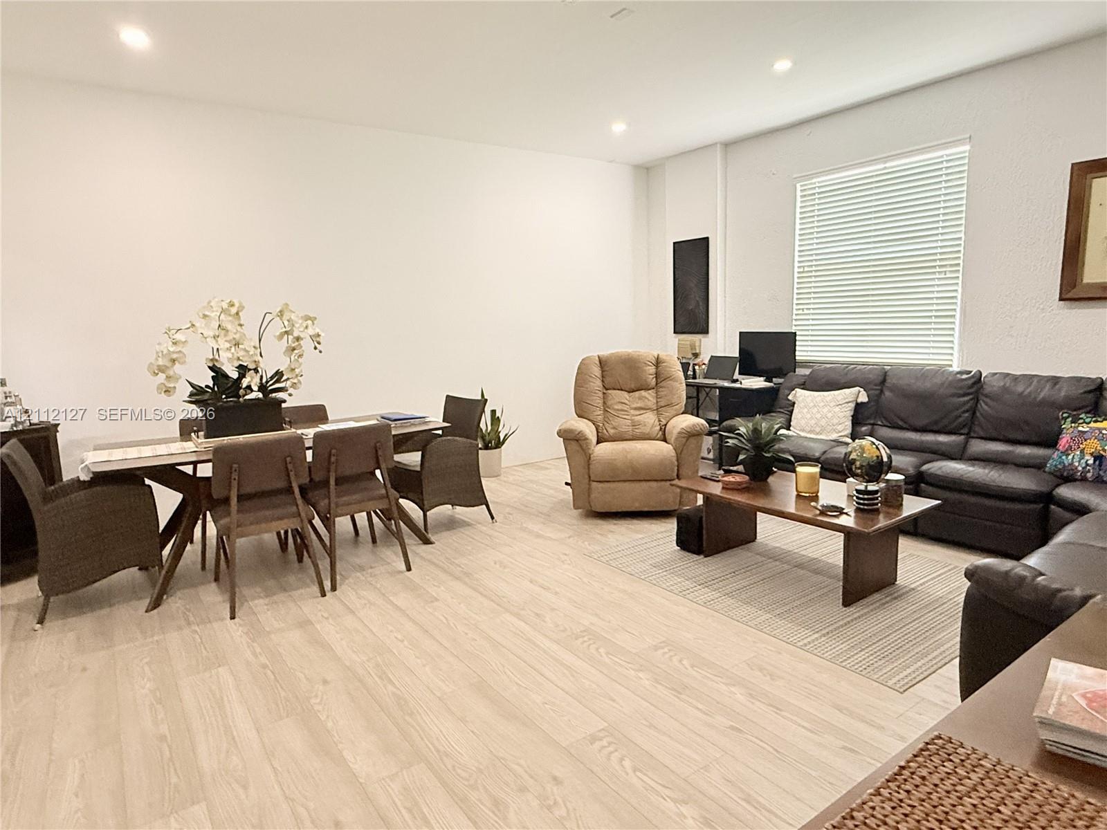 Light-toned wood-finish flooring, recessed lighting, and large window with blinds