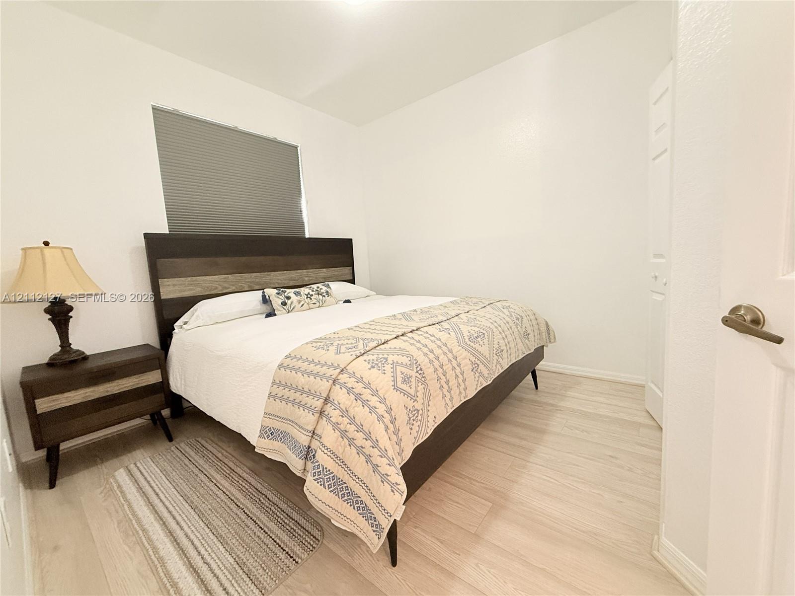 Neutral-toned wall finish, wood-finish flooring, and a window with a fitted cellular shade