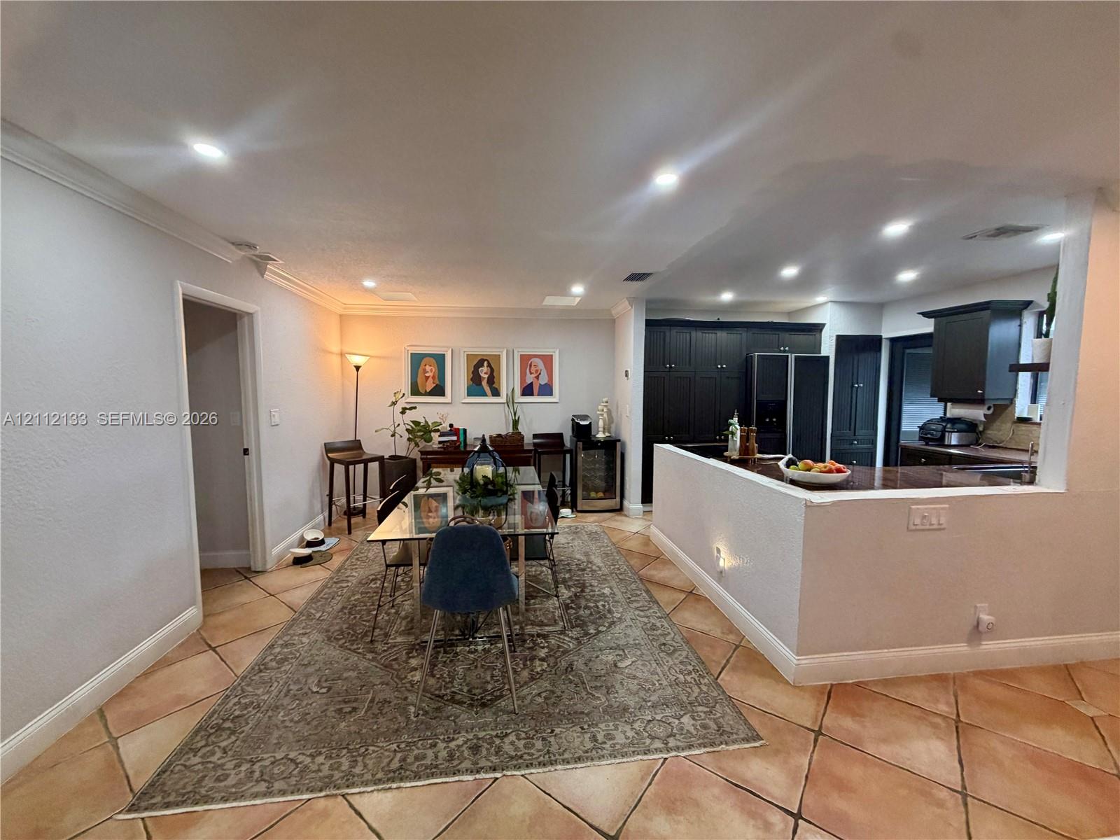 Ceramic tile flooring, recessed ceiling lighting, and dark-toned cabinetry with a peninsula counter