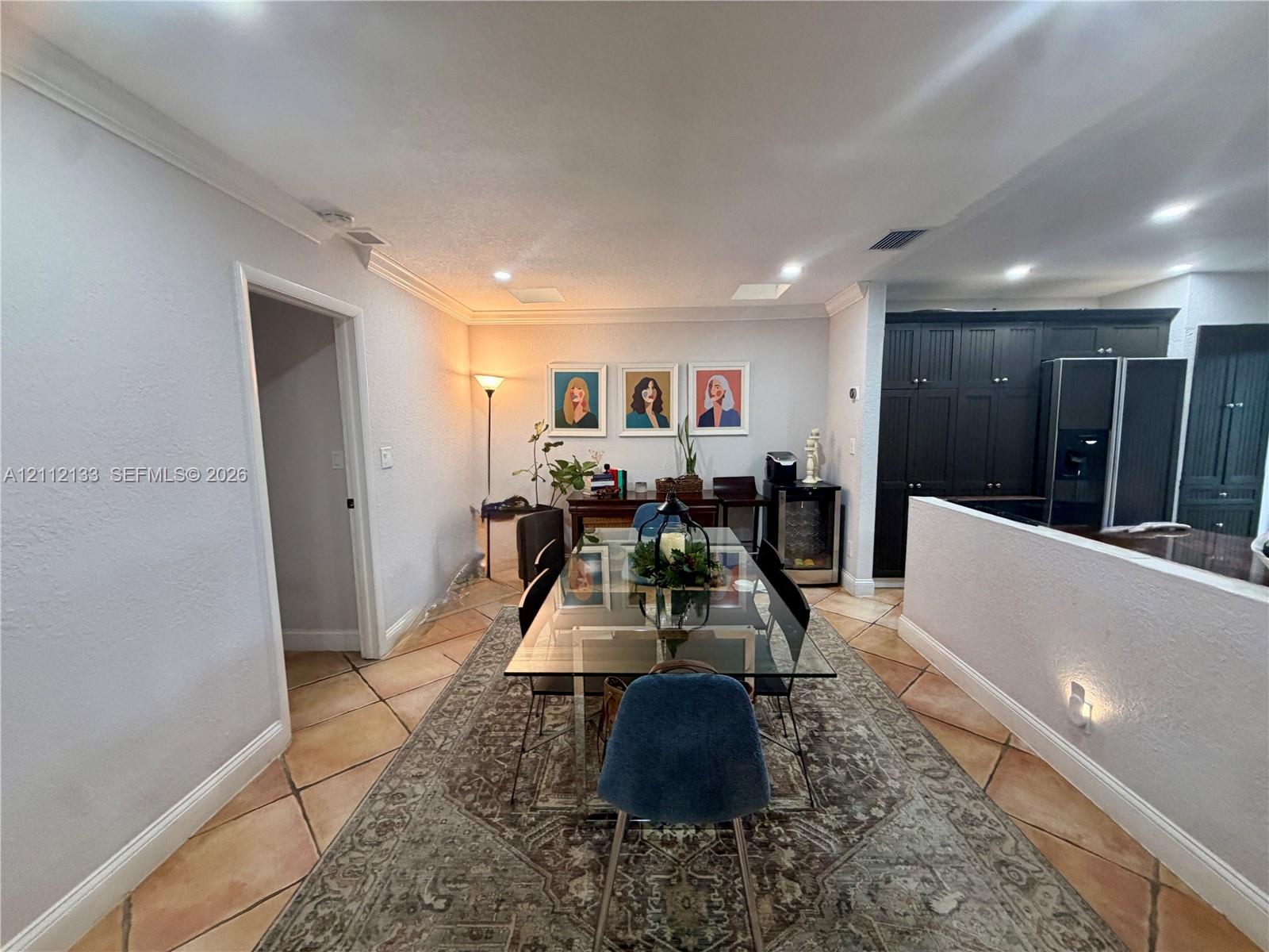 Neutral-tone walls with crown molding, square tile flooring, recessed lighting, and dark-finish built-in cabinetry