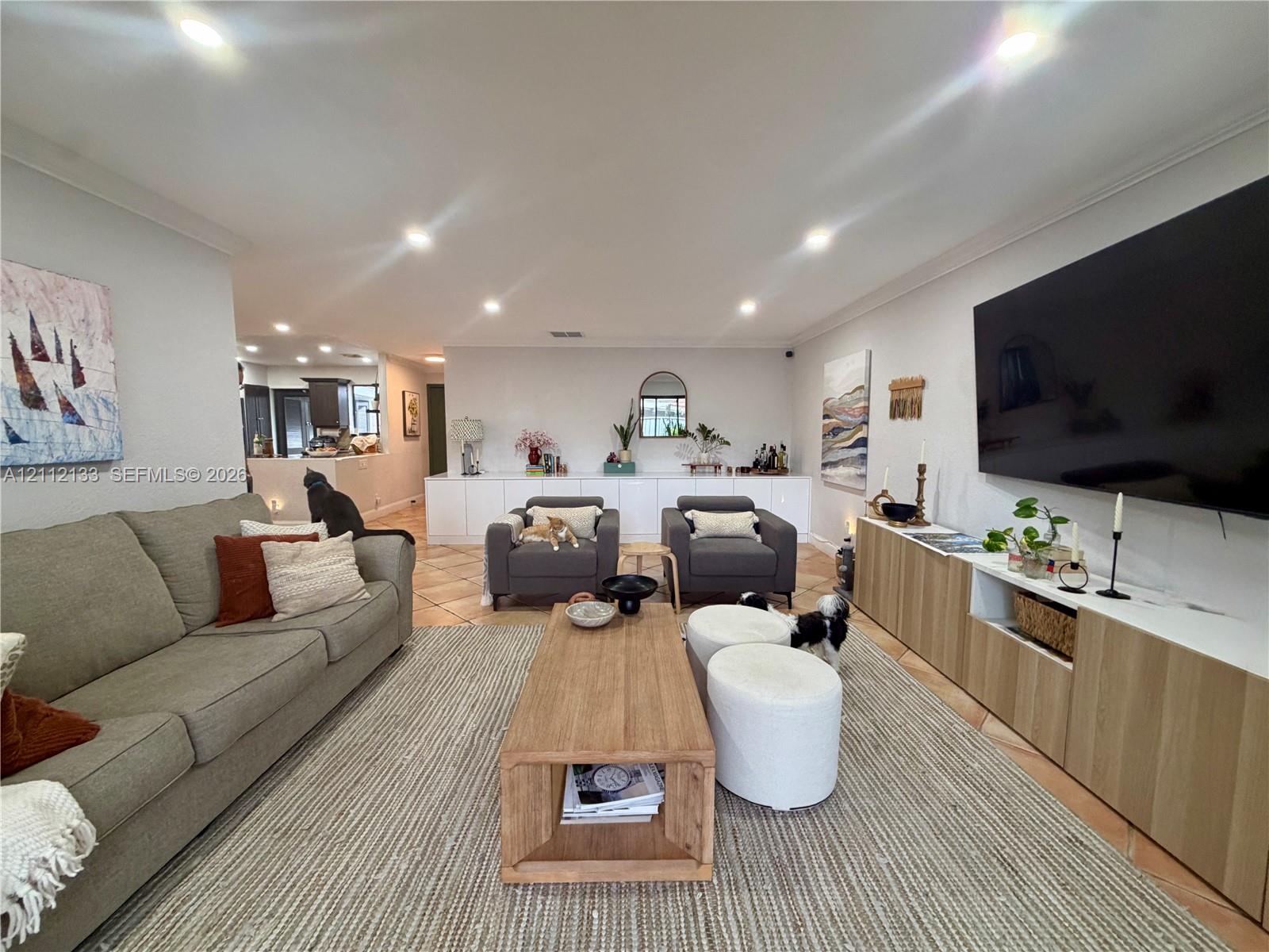 Living area featuring recessed lighting, tile flooring, and custom built-in cabinetry with wood-grain finish doors