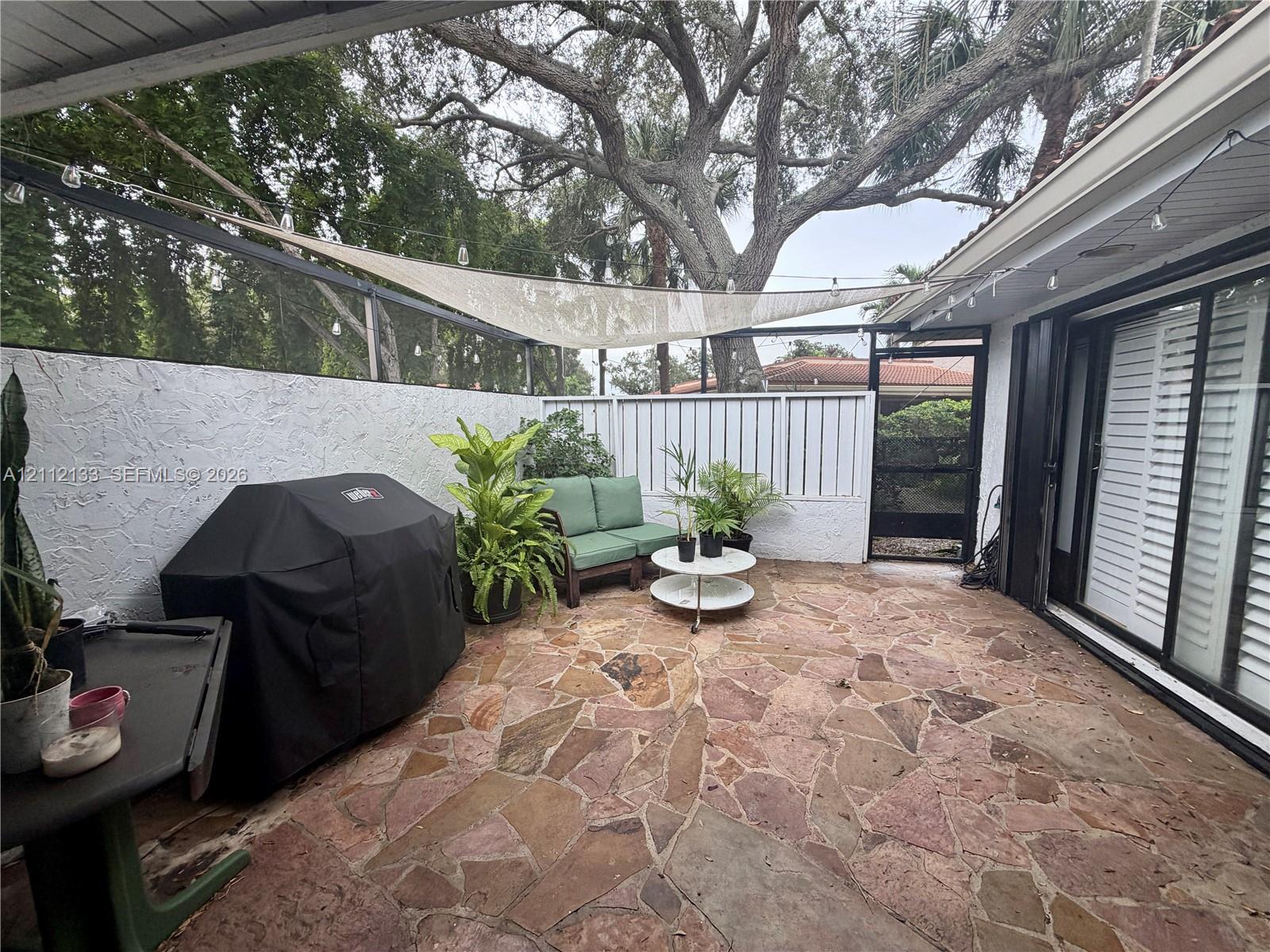 Screen-enclosed patio featuring flagstone flooring, textured masonry wall, and sliding glass doors