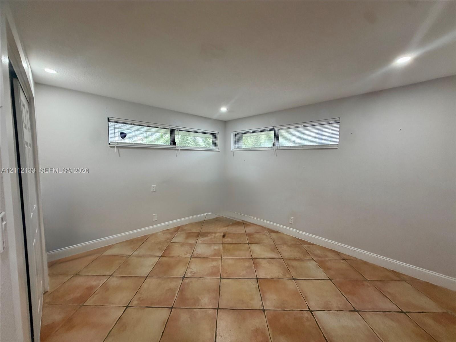 Interior space featuring neutral wall paint, tile flooring, two horizontal sliding windows, and recessed lighting