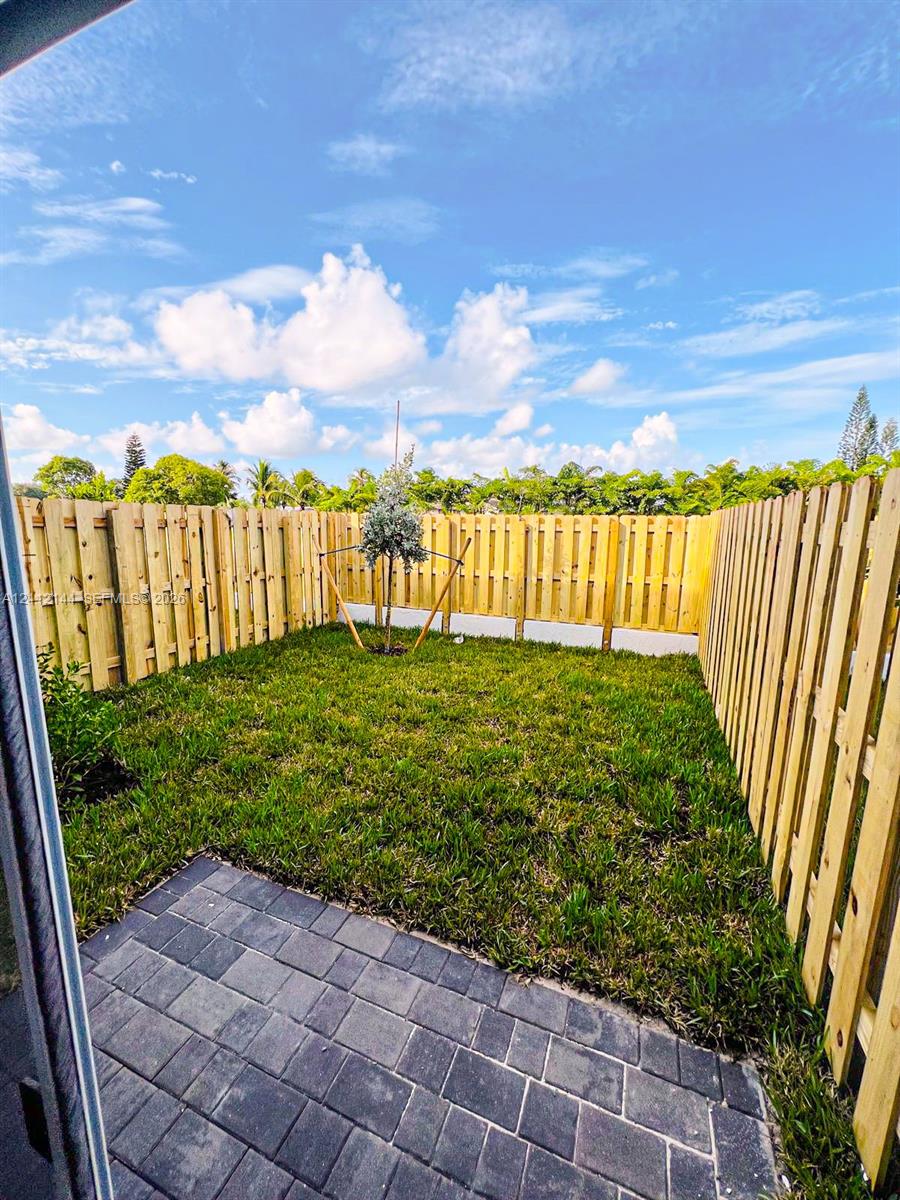 Private backyard featuring a paved stone patio, natural grass lawn, and full-perimeter wood fencing